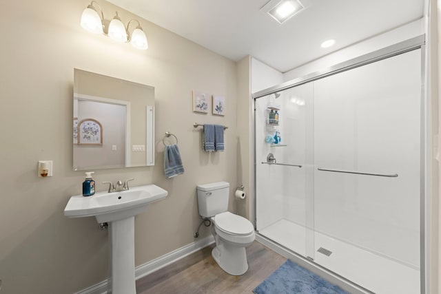 bathroom with toilet, baseboards, wood finished floors, and a stall shower