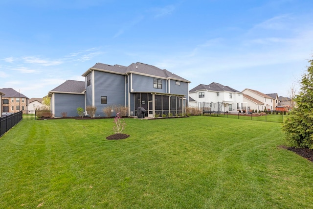 rear view of property featuring a residential view, a lawn, a sunroom, and a fenced backyard