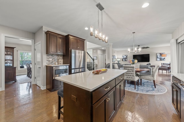 kitchen with light countertops, hanging light fixtures, stainless steel appliances, and dark brown cabinets
