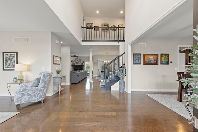 entrance foyer with stairs, baseboards, visible vents, and a high ceiling