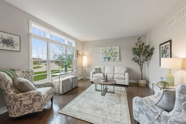 living area with baseboards, visible vents, and dark wood finished floors