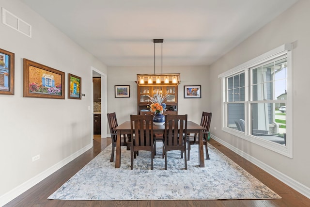 dining area with baseboards, dark wood-type flooring, and visible vents