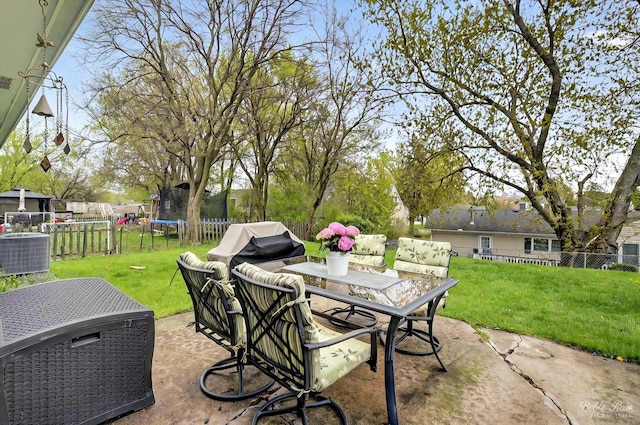 view of patio / terrace featuring central air condition unit, a fenced backyard, outdoor dining area, and a trampoline