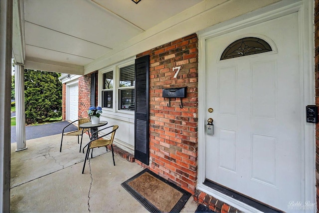 doorway to property with a porch and brick siding