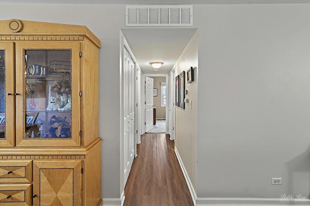 hallway with visible vents, baseboards, and wood finished floors