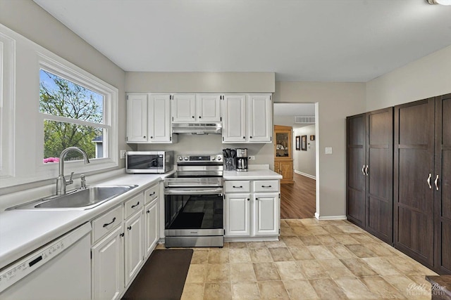 kitchen featuring appliances with stainless steel finishes, a sink, light countertops, white cabinets, and under cabinet range hood