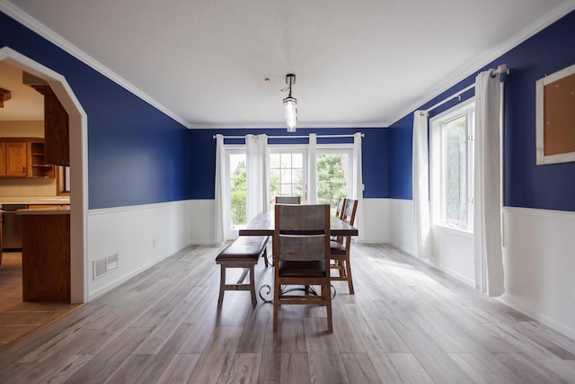 dining space with wood finished floors, crown molding, visible vents, wainscoting, and arched walkways