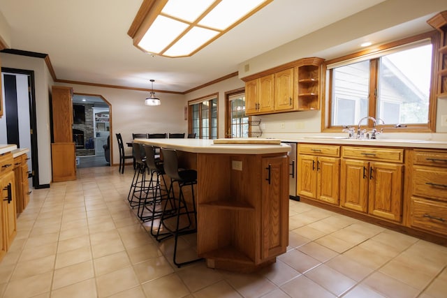 kitchen with a kitchen bar, a sink, open shelves, crown molding, and a kitchen island