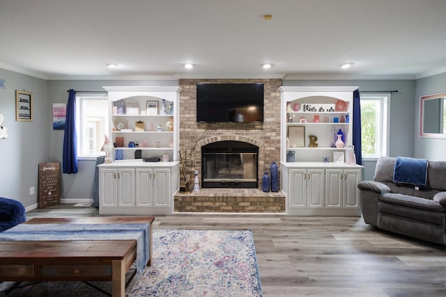 living room featuring ornamental molding, light wood-style floors, a brick fireplace, and baseboards