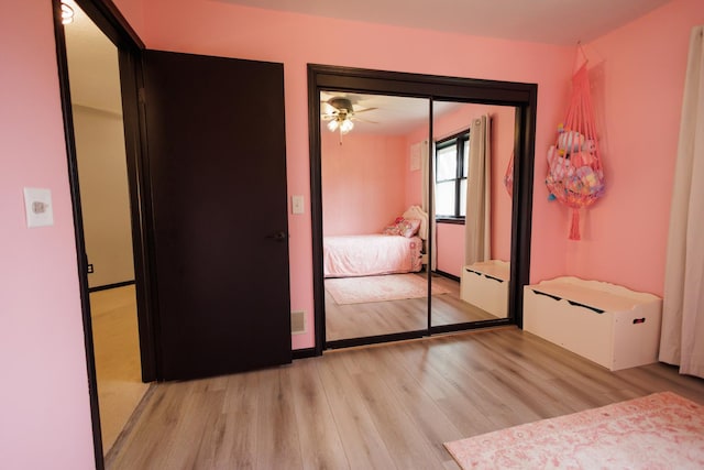 unfurnished bedroom featuring a ceiling fan, a closet, and light wood-style flooring
