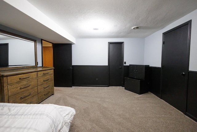 bedroom with light colored carpet and a textured ceiling
