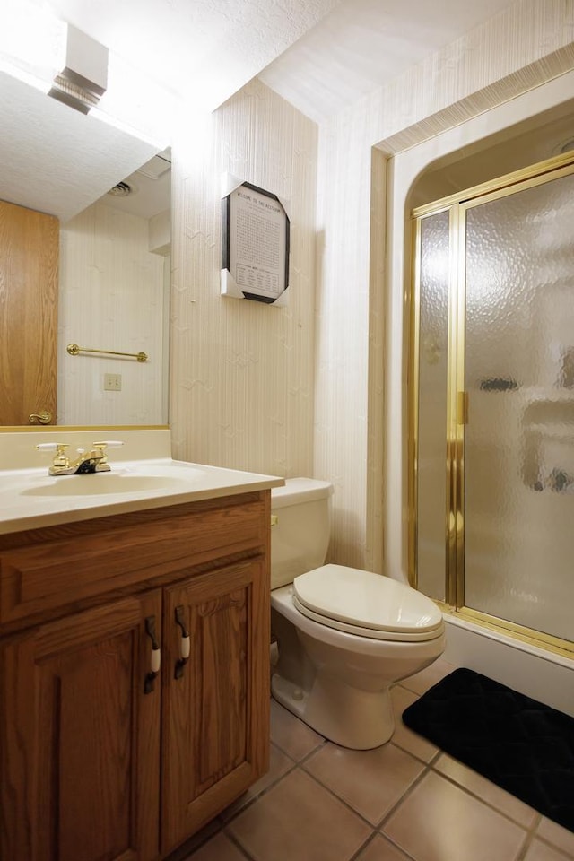 bathroom with toilet, wallpapered walls, tile patterned flooring, a shower stall, and vanity
