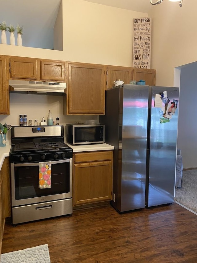 kitchen with dark wood-style floors, light countertops, stainless steel appliances, and under cabinet range hood