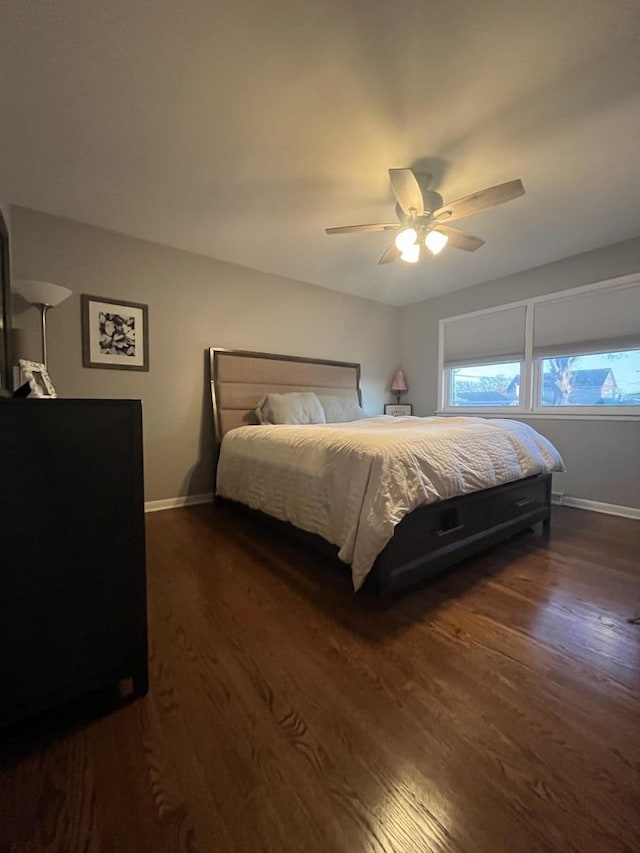 bedroom with ceiling fan, dark wood-style floors, and baseboards