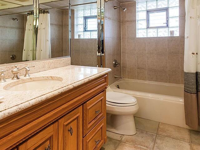 bathroom with shower / tub combo, toilet, and vanity