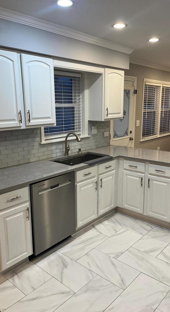 kitchen featuring tasteful backsplash, stainless steel dishwasher, white cabinets, and crown molding