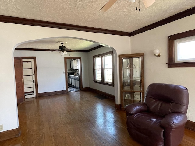 living area with arched walkways, ceiling fan, and dark wood-style flooring