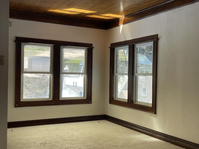 carpeted empty room featuring wood ceiling and baseboards