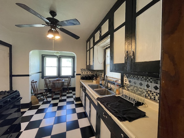 kitchen featuring decorative backsplash, a sink, dark floors, black gas stove, and light countertops