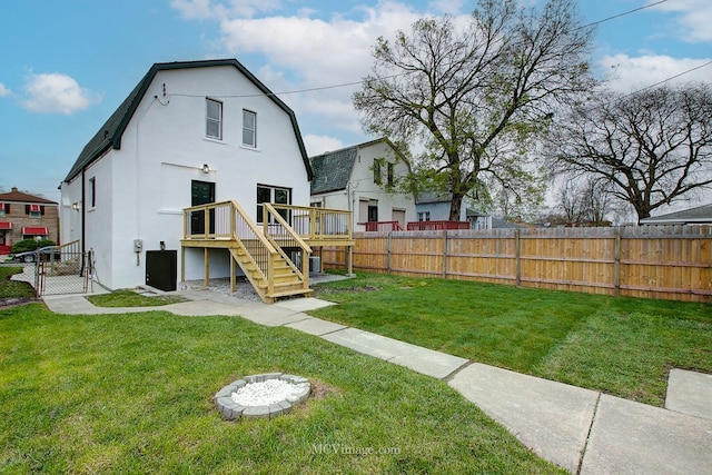 9221 S Lowe Ave, Chicago, IL 60620 - back of property with a gambrel roof, a wooden deck, a fenced backyard, a lawn, and stucco siding