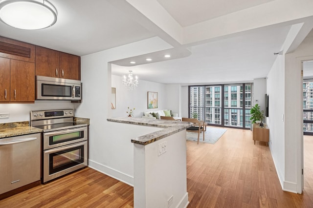 kitchen featuring recessed lighting, a peninsula, appliances with stainless steel finishes, light wood finished floors, and open floor plan