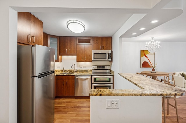 kitchen featuring recessed lighting, glass insert cabinets, a kitchen breakfast bar, light wood-style flooring, and appliances with stainless steel finishes
