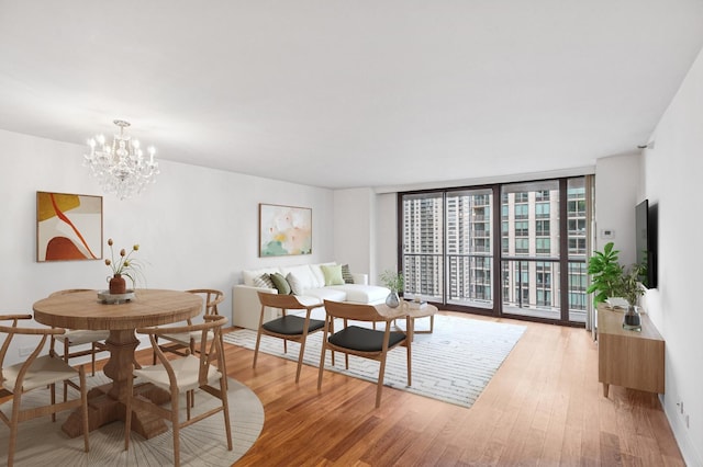 dining space featuring a chandelier, light wood-style floors, and floor to ceiling windows