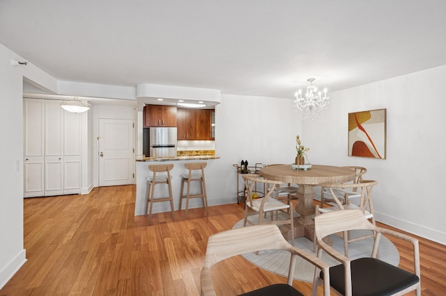 dining room featuring an inviting chandelier, baseboards, and light wood-type flooring