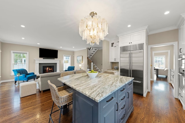 569 Prairie Ave, Glen Ellyn, IL 60137 - kitchen with built in refrigerator, white cabinets, ornamental molding, a kitchen island, and dark wood-style flooring