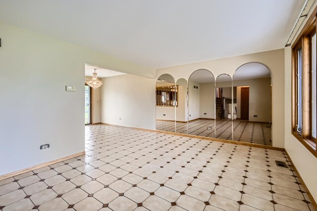 unfurnished living room with arched walkways, baseboards, and visible vents