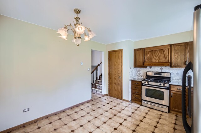 kitchen with brown cabinetry, tasteful backsplash, gas stove, baseboards, and an inviting chandelier