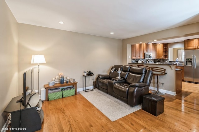 living area featuring recessed lighting, light wood finished floors, and baseboards