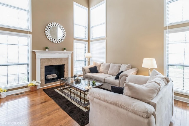 living area with a high ceiling, visible vents, wood finished floors, and baseboards