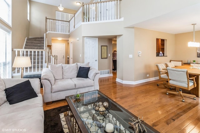 living area with stairway, wood finished floors, visible vents, and baseboards