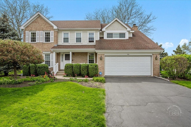 traditional-style house with a chimney, a front yard, brick siding, aphalt driveway, and an attached garage
