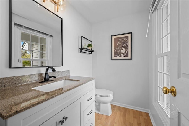 bathroom featuring toilet, baseboards, wood finished floors, and vanity