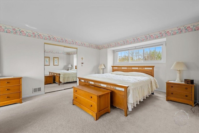 bedroom with baseboards, visible vents, light carpet, and a closet