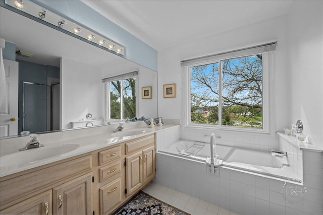 bathroom featuring double vanity, tile patterned floors, a sink, and a bath