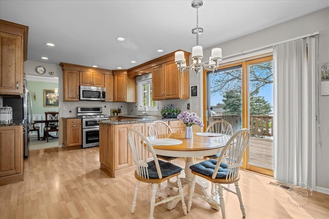 kitchen featuring a sink, a chandelier, brown cabinetry, stainless steel appliances, and visible vents
