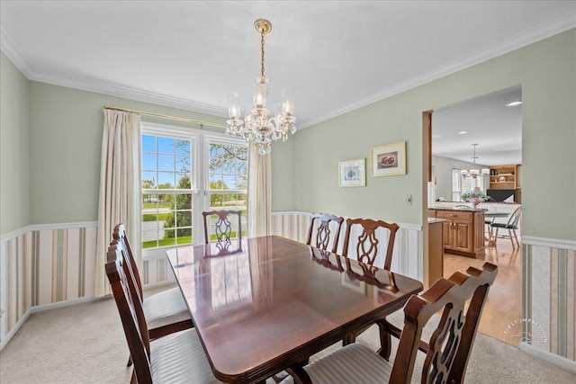 dining space with ornamental molding, light colored carpet, and a chandelier