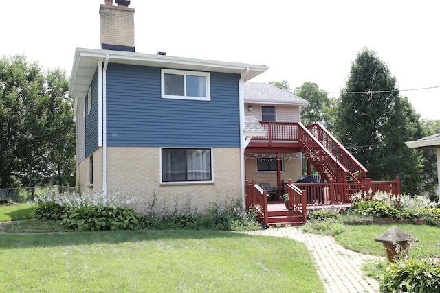 rear view of property featuring a chimney, a yard, brick siding, and a wooden deck