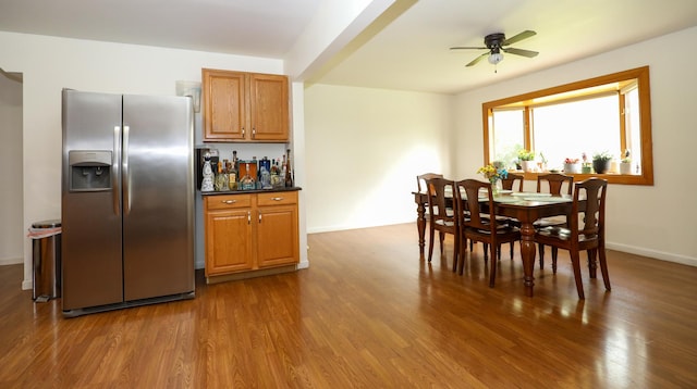 dining room with dark wood-style flooring, ceiling fan, a bar, and baseboards