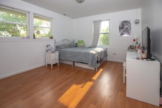 bedroom featuring baseboards, visible vents, multiple windows, and light wood-style flooring