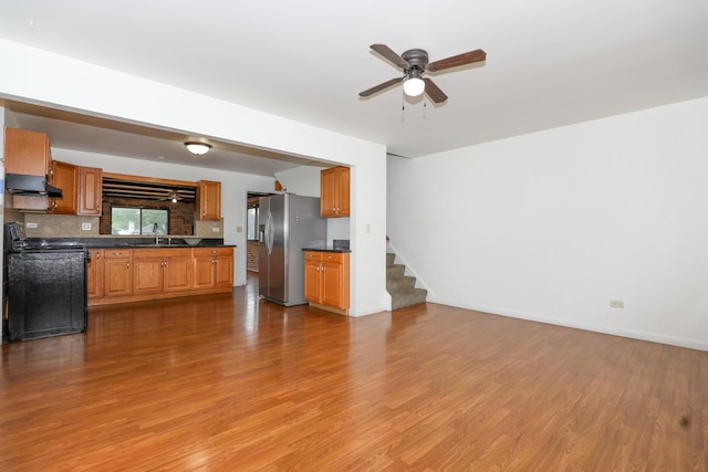 18557 W Country Ln, Grayslake, IL 60030 - unfurnished living room featuring a ceiling fan, light wood-type flooring, a sink, stairs, and baseboards