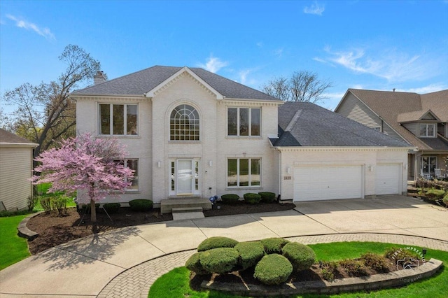 colonial-style house featuring a garage, a chimney, concrete driveway, and a shingled roof