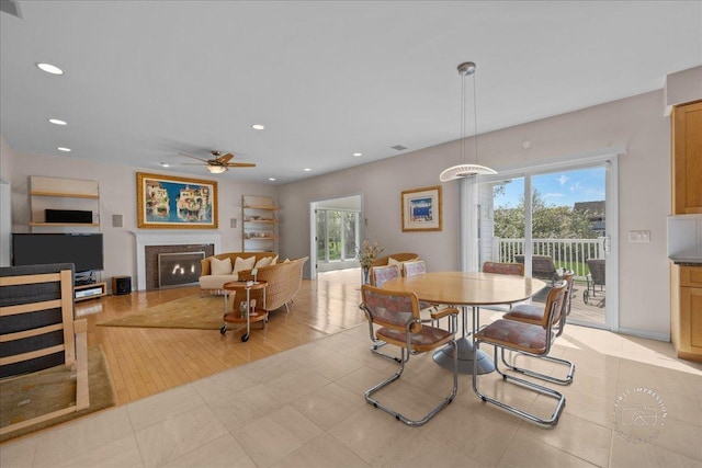 dining space with recessed lighting, ceiling fan, a glass covered fireplace, and a healthy amount of sunlight