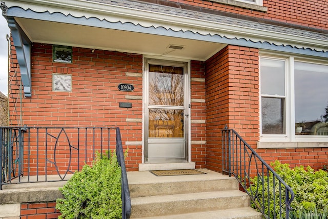entrance to property featuring brick siding and fence