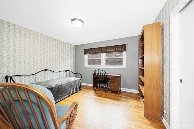 bedroom featuring wallpapered walls, hardwood / wood-style flooring, an accent wall, and baseboards