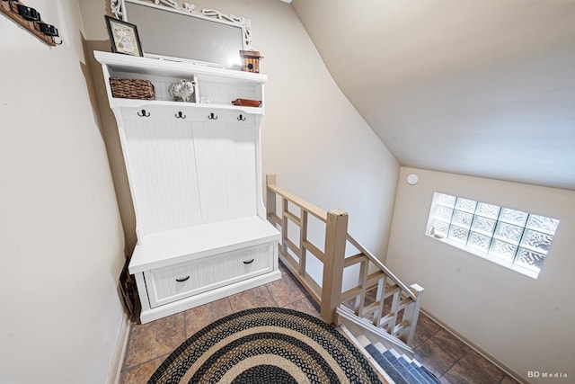 mudroom with baseboards, stone tile floors, and vaulted ceiling