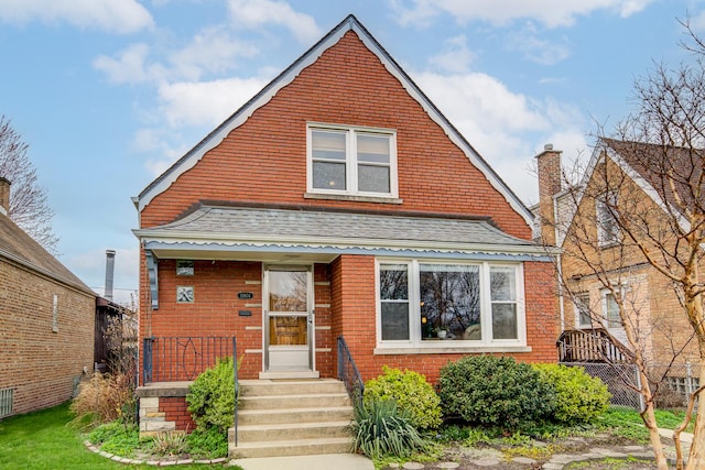 view of front of property with roof with shingles and brick siding